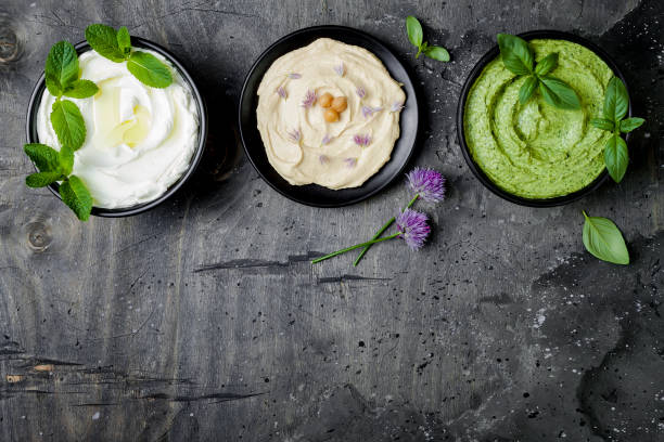 istock Vegetarian dip table. Yogurt sauce or labneh, hummus, herb hummus or pesto. Middle eastern meze snacks set. Copy space, flat lay, overhead 986069388