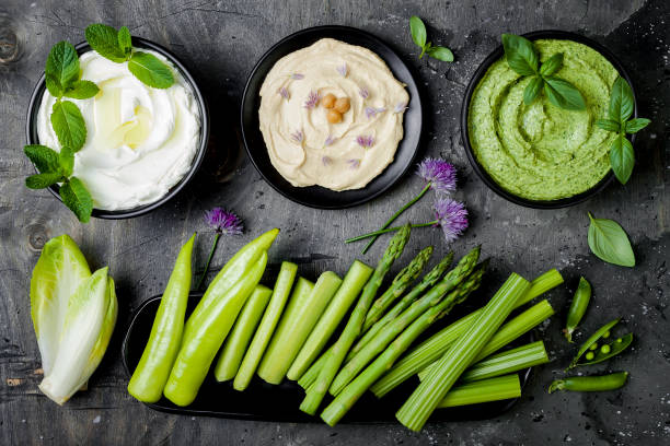 istock Green vegetables raw snack board with various dips. Yogurt sauce or labneh, hummus, herb hummus or pesto with fresh vegetables. Middle eastern meze snacks set 986069400