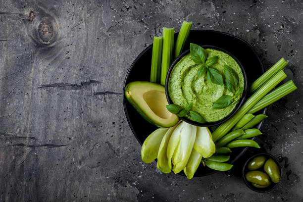 istock Green vegetables snack board with herb hummus or pesto dip. Healthy raw summer appetizer platter. Copy space 986081014