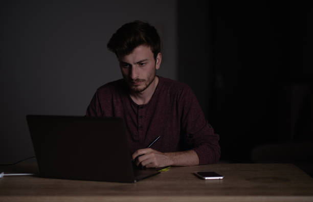 istock Young student looking studying during the night on the computer. Tired student with exhausted look. Sleepy designer working during the night. 986088866