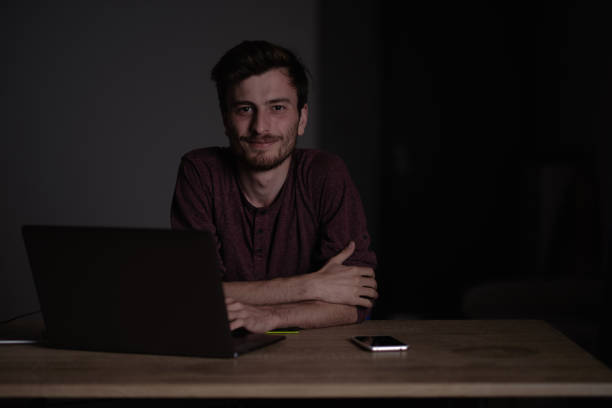 Young student looking at camera with a little smile. Tired student with exhausted look. Sleepy programmer working during the night. stock photo