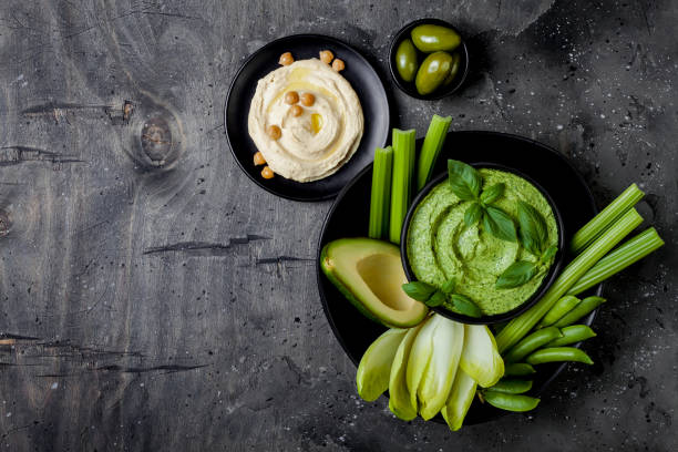 istock Green vegetables snack board with herb hummus or pesto dip. Healthy raw summer appetizer platter. Copy space 986091566