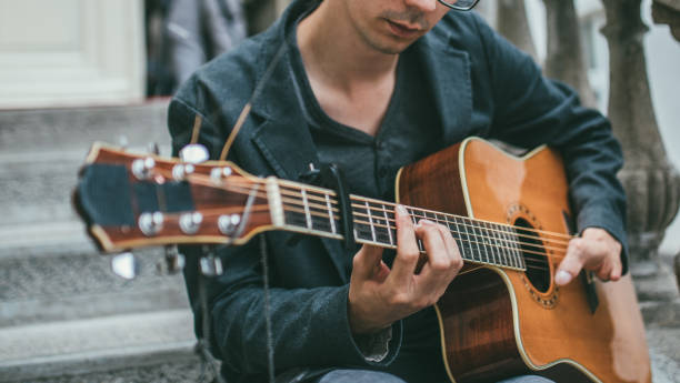 istock Young man with differing abilities playing acoustic guitar outdoors 986092512