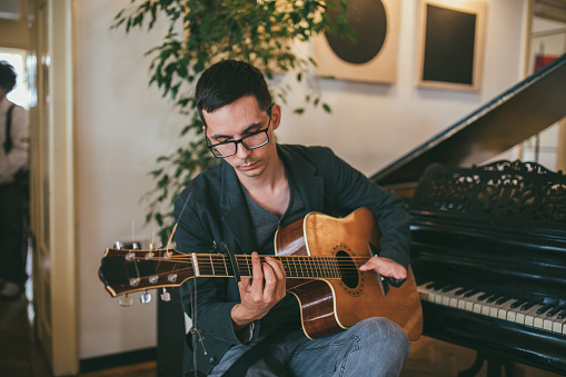 Young man with differing abilities playing acoustic guitar