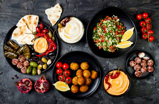 Arabic traditional cuisine. Middle Eastern meze platter with pita, olives, hummus, stuffed dolma, labneh cheese balls in spices. Mediterranean appetizer party idea stock photo