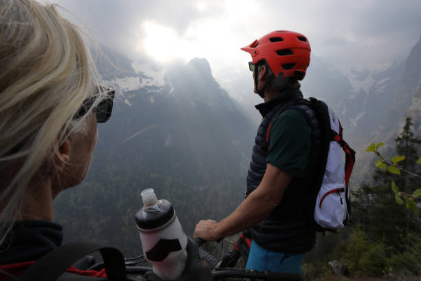 mature man and woman mountain bikers look out to mountains - 24252 imagens e fotografias de stock