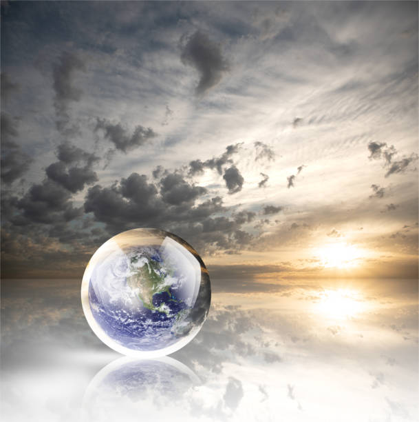 istock Crystal ball reflecting globe of the earth on sunset with clouds background 986141072