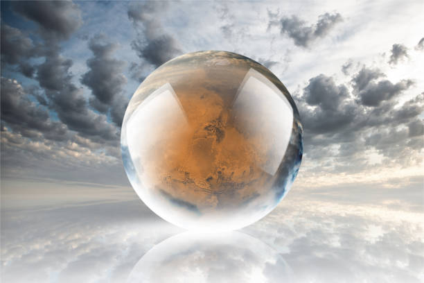 istock Crystal ball reflecting globe of the mars on clouds background 986154334