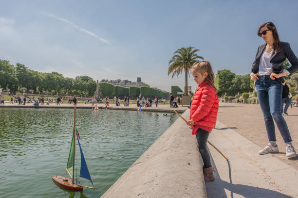 jeune fille guides un voilier au jardin du luxembourg à paris - jardin luxembourg photos et images de collection