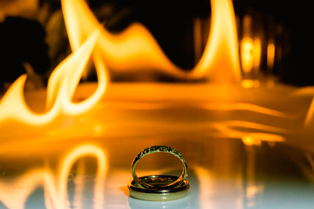 Gold Wedding Rings on White Plate with Fire in the Background with Party Decorations