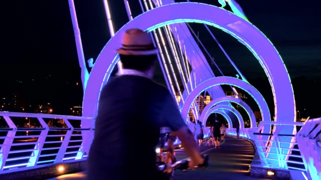 People riding bike on Yangguang Bridge at dusk, New Taipei, Taiwan