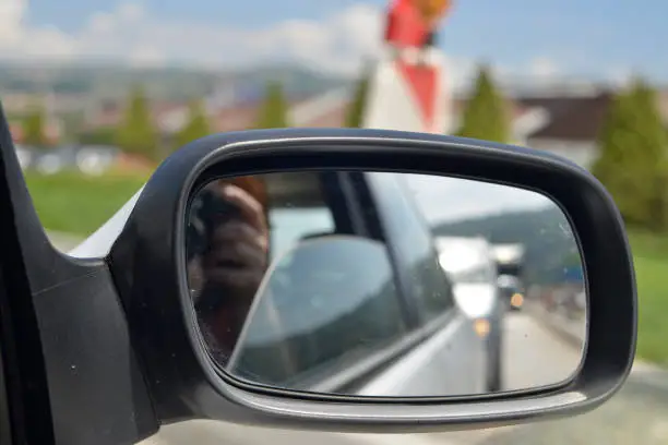 Photo of A woman photographs a traffic jam in the car mirror