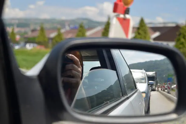 Photo of A woman photographs a traffic jam in the car mirror
