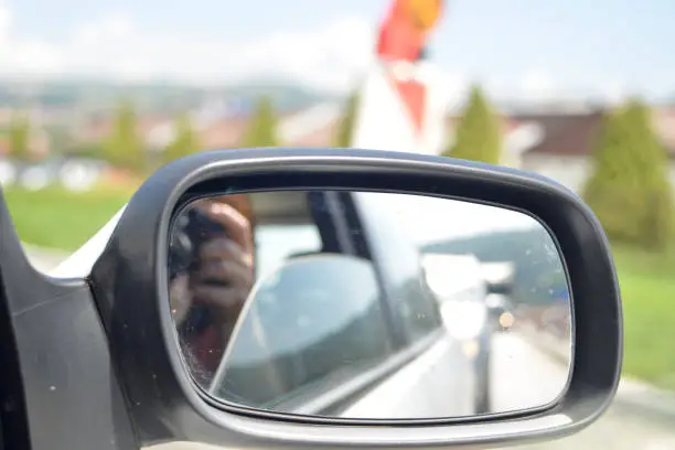 Photo of A woman photographs a traffic jam in the car mirror