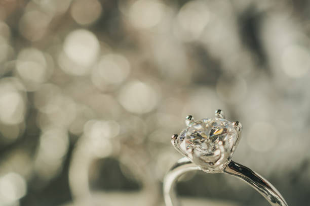 istock luxury engagement Diamond ring with abstract bokeh light background 986208014