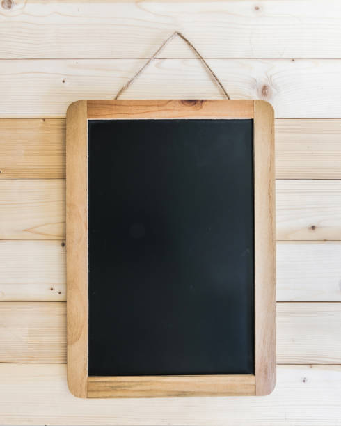istock Blank black chalkboard frame with copyspace hanging on pine wood wall for announcement and restaurant menu 986208046