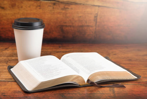 Bible and a Cup of Coffee in a Disposable Paper Cup on a Wooden Table