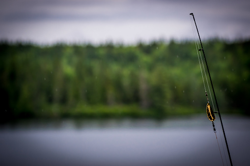 Fishing rod ready to go with the lake and forest in background in Quebec, Canada
