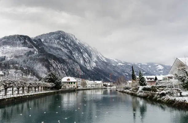 A river view in a town at the foot of a snow mountain on a cloudy day. It is in Interlaken