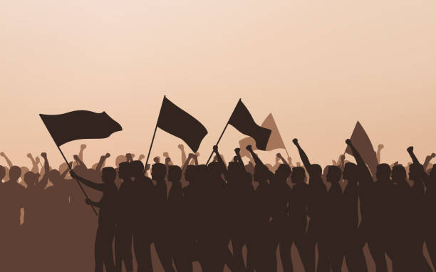 istock Silhouette group of people Raised Fist and flags Protest in flat icon design with evening sky background 986270770