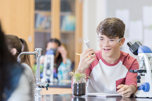 A teenage boy stares into a test tube with a look of awe during High School science class.