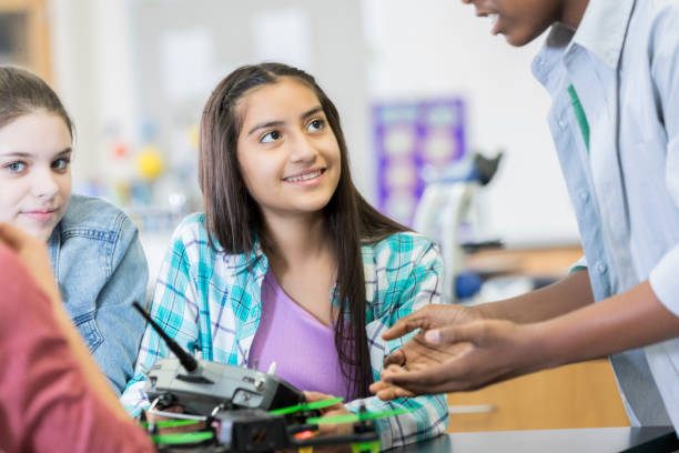 istock Teenage girl listens to classmate explain robotics controller 986272250