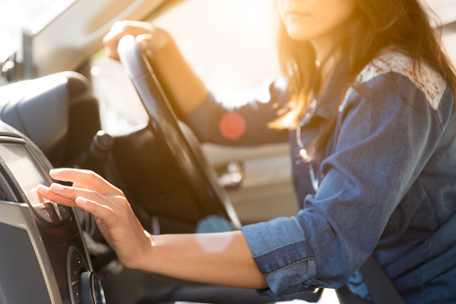 woman driver hand touching the screen entering an address into the navigation system and turning on car radio system.
