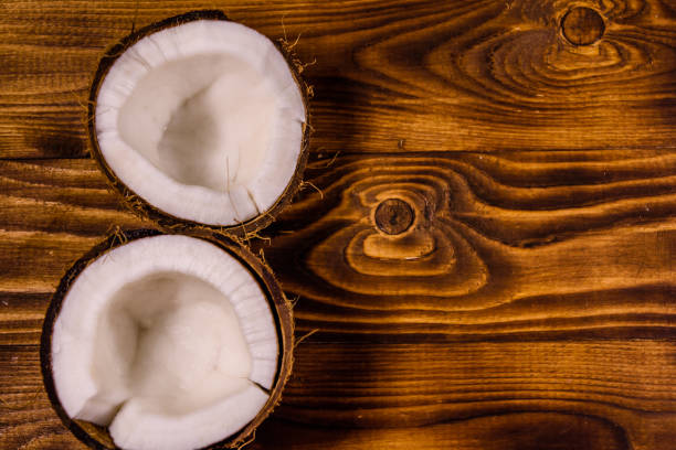 istock Ripe halved coconut on a wooden table. Top view 986301924
