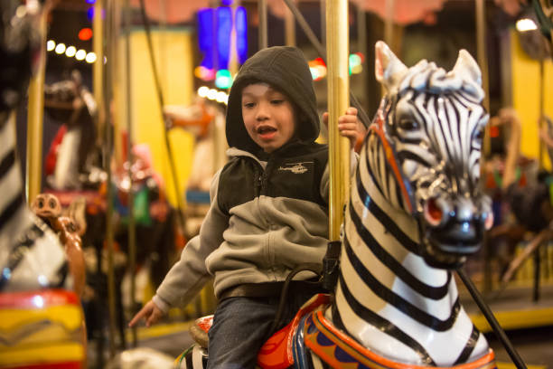 istock Kids enjoying a them parks Merry go round 986331446