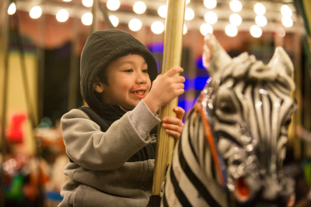 istock Kids enjoying a them parks Merry go round 986331540