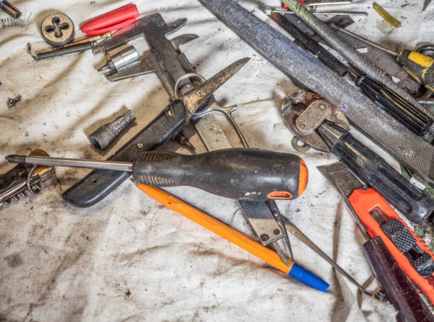 istock Dirty set of hand tools on a home workbench close up. Home workbench covered with white dirty sheet full of dusty hand tools. An untidy home worktop full of different hand instruments, close up 986354358