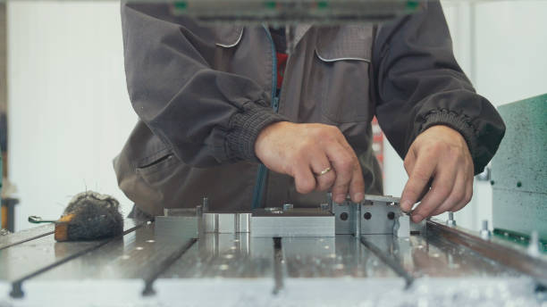 istock Worker with a scraper chamfering removing burrs on metal object for manufacturing industrial CNC machines 986380058