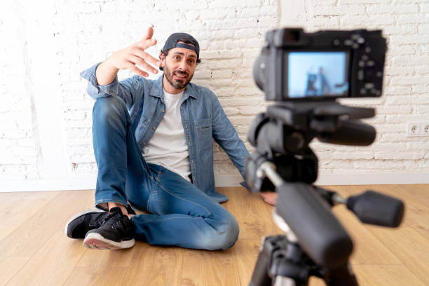istock young attractive man in casual clothes hat beard hipster style with video camera on tripod against brick wall background in internet blog and blogger concept. 986395798