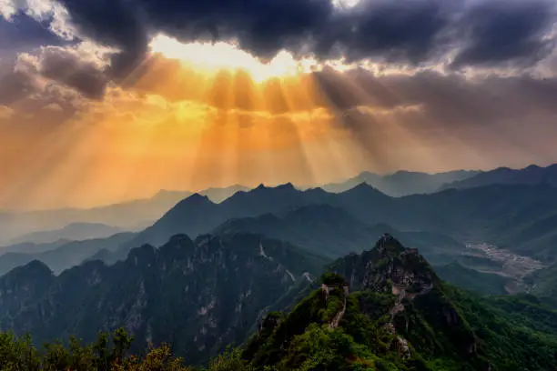 A dramatic sky with the sun breaking through the clouds in the Great Wall of China.