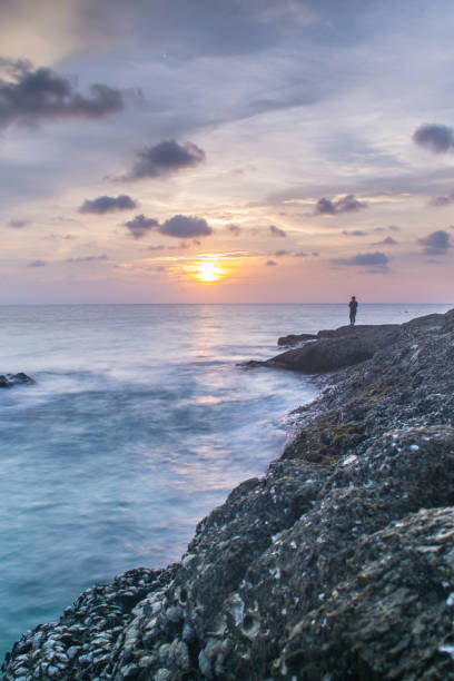 istock colorful sunset with waves splash on coast and blurr front pacific oyster rock at surin beach andaman ocean 986418588