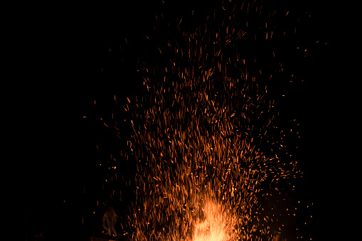 A glowing log fire in an open fireplace with firewood fuel.