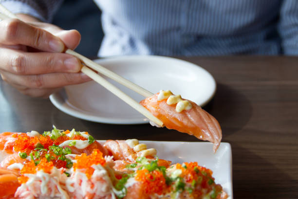 istock People use chopsticks to pick up sushi. 986427182