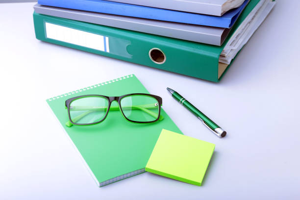 istock Work place table with folders file on it and modern laptop, pen, glasses and textbook lying near on a white background. 986427670