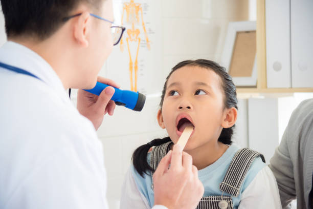 girl open her mouth for doctor doing oral examination stock photo