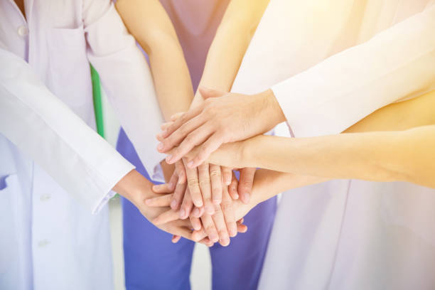 istock Doctors and nurses in a medical team stacking hands 986429752