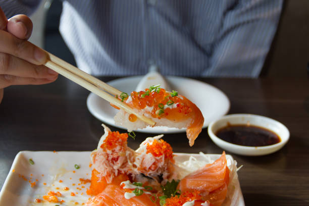 istock People use chopsticks to pick up sushi. 986433084