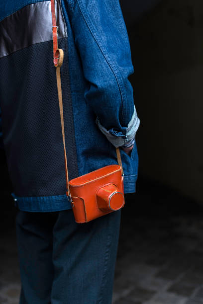 istock Man in jeans jacket with vintage film camera in a leather case 986433116