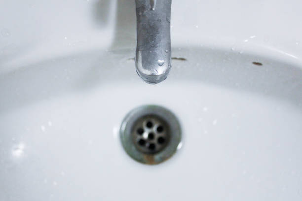 istock Water droplet, drain in white washbasin 986436638
