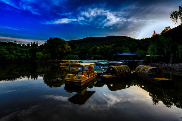 A colorful scenery under the Chinese springtime sun, paddle boats in the garden lake during the blue hour.