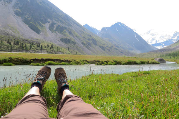 istock Female legs on the grass and mountains landscape on background 986464040