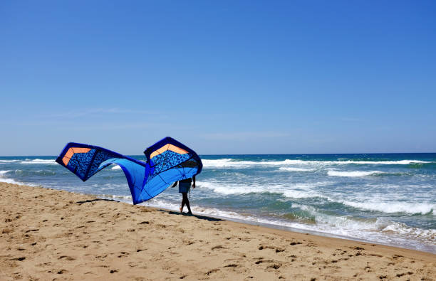 Man surfer in wetsuits with kite equipment for surfing Man surfers in wetsuits with kite equipment for surfing, in Sabaudia, Lazio, Italy sabaudia stock pictures, royalty-free photos & images