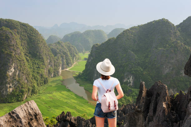 istock Young tourist with backpack enjoying valley view from top of a mountain 986471136
