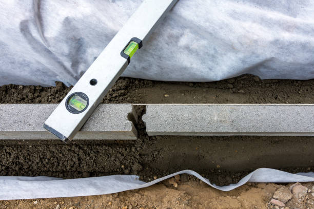 Setting of edge restraints with border stones in concrete with bubble level Setting edge restraints buy putting border curb stones in earth-moist concrete with bubble level kerbstone stock pictures, royalty-free photos & images