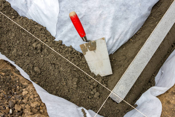 Setting edge restraints with border stones in concrete Setting edge restraints buy putting border curb stones in earth-moist concrete with trowel kerbstone stock pictures, royalty-free photos & images