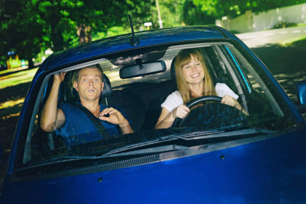 istock Driving lesson: terrified man teaching  happy girlfriend to drive 986474444